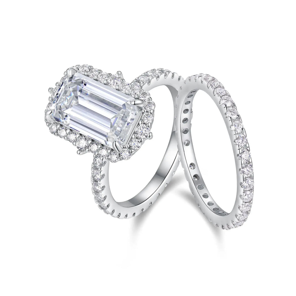 Diamond ring with emerald-cut center stone on a white background