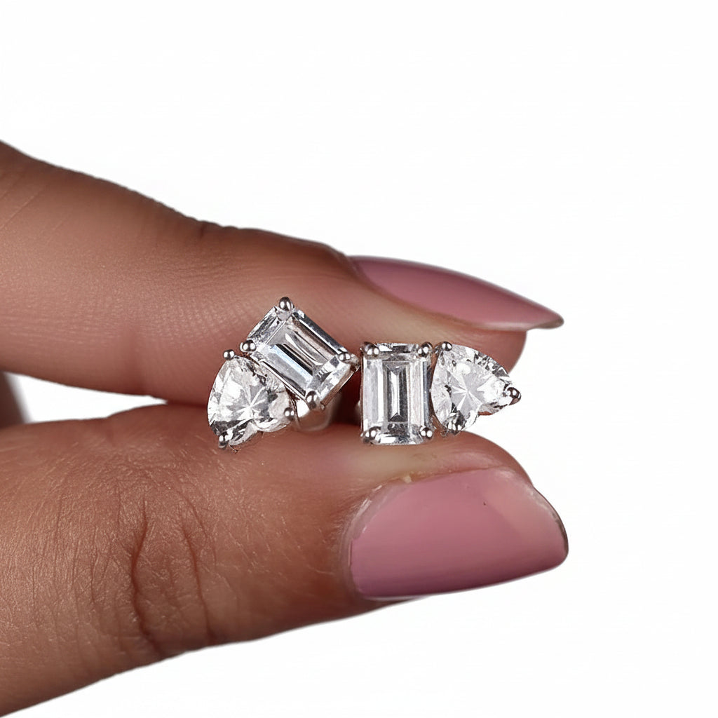 Pair of diamond earrings held between fingers with a white background