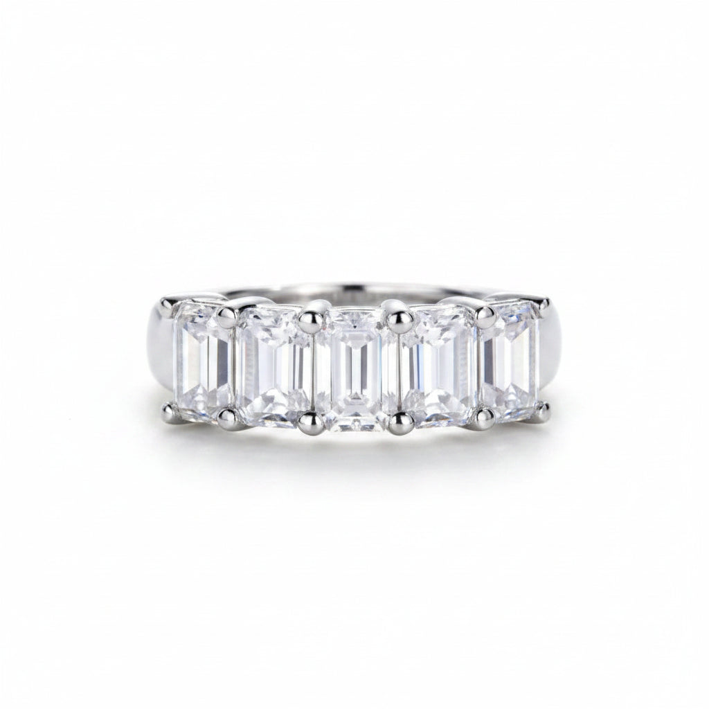 Silver ring with emerald-cut gemstones on a white surface