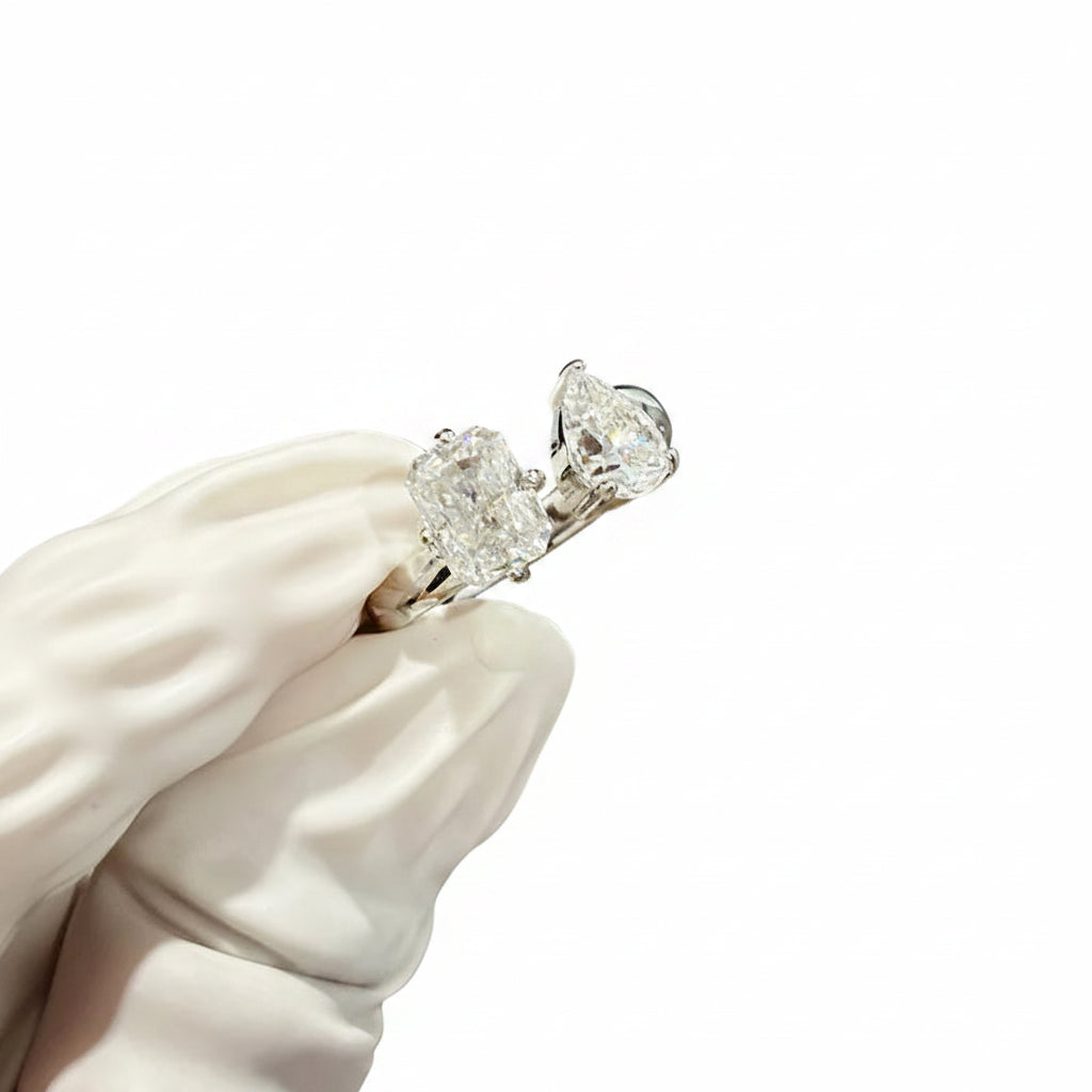Moissanites earring held by a gloved hand against a white background