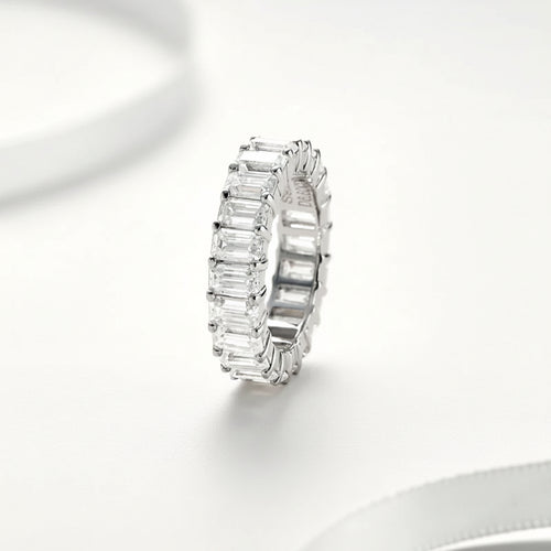 Moissanite ring with emerald-cut stones on a white background
