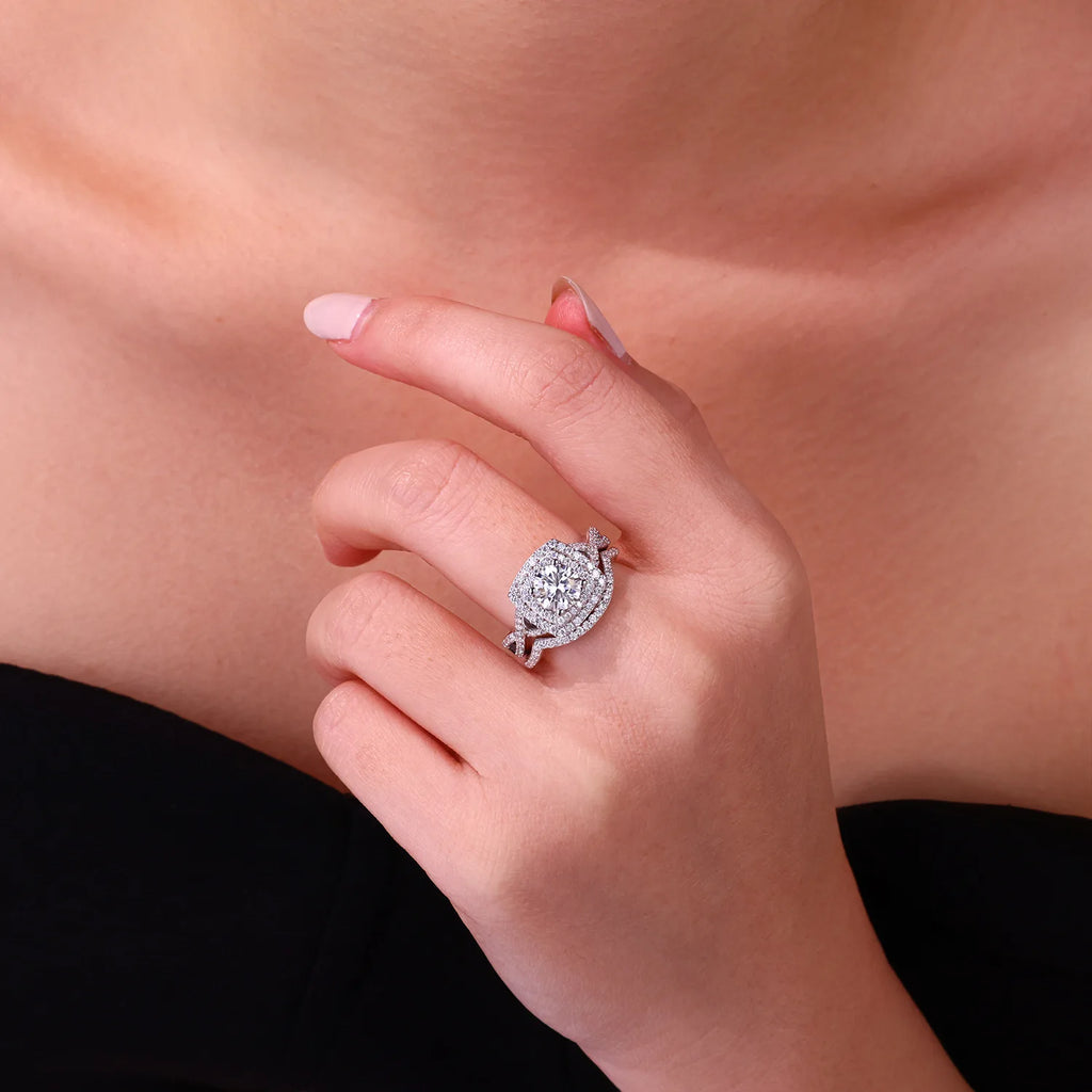 Close-up of a hand wearing a silver ring with a moissanite diamond on a neutral background