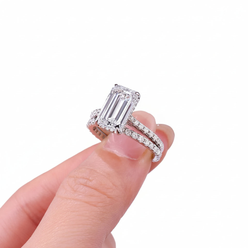 Diamond ring held by a hand against a white background