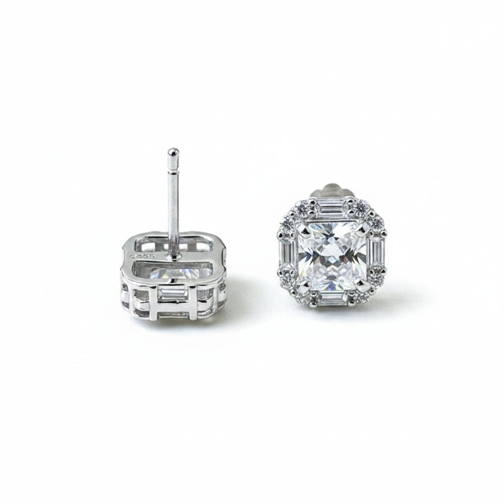 Pair of silver earrings with clear gemstones on a white surface