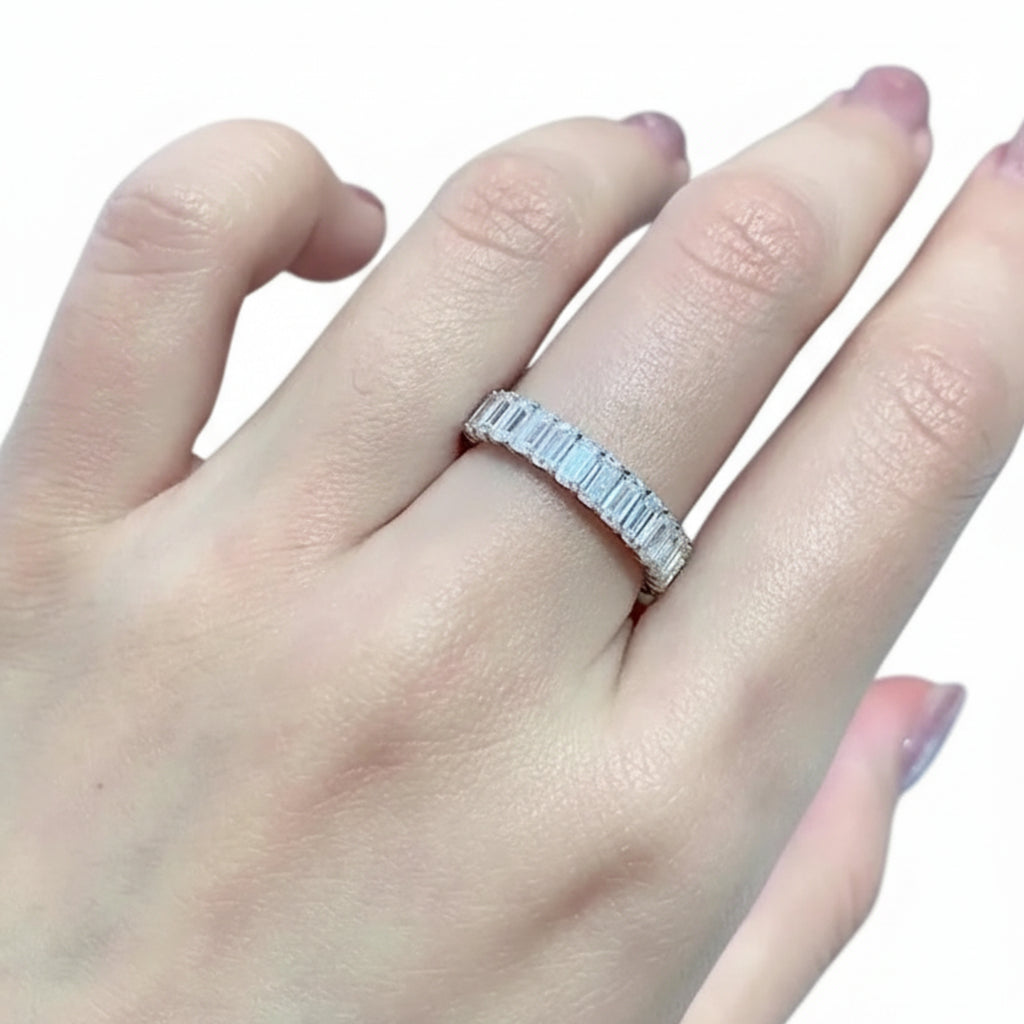 Hand wearing a silver ring with gemstones on a blurred background
