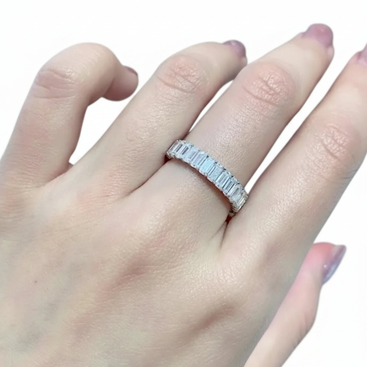 Hand wearing a silver ring with gemstones on a blurred background