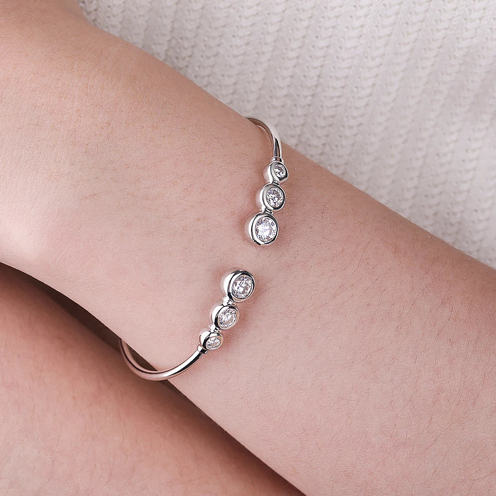 Silver bracelet with moissanite stones on a person's wrist against a light background
