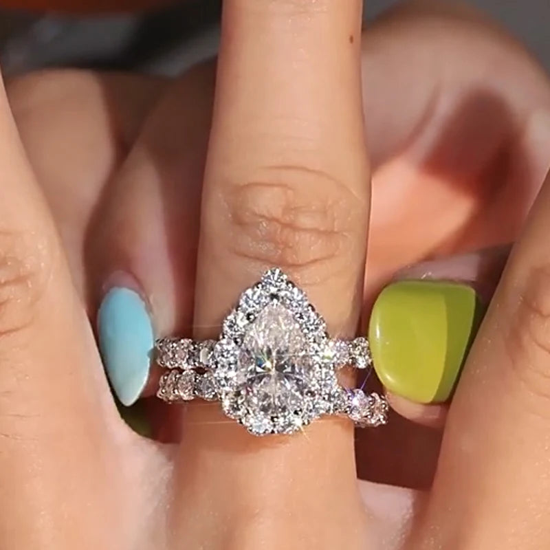 Close-up of a hand wearing a moissanite ring with green and blue nail polish.