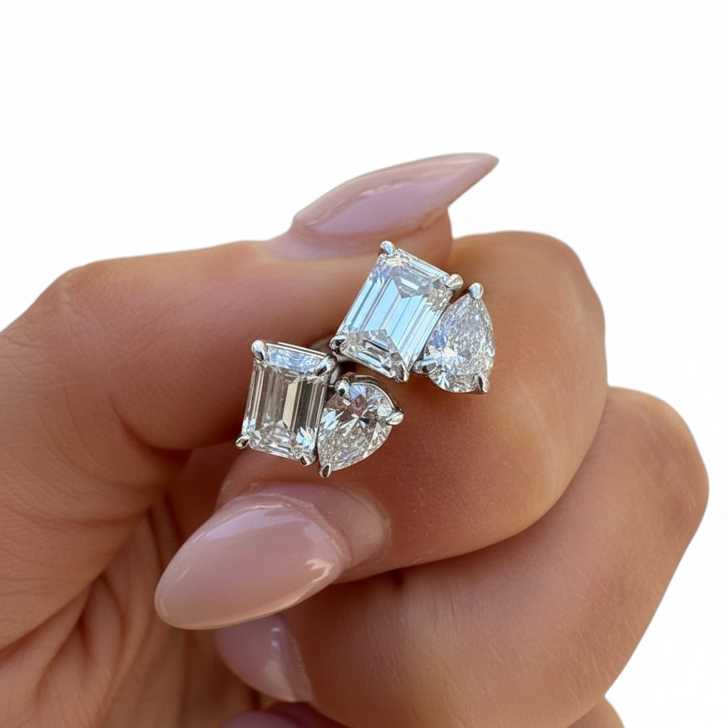 Diamond earrings held in a hand with a white background