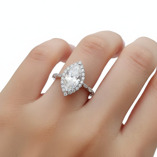 Silver ring with a large moissanite gemstone on a hand.