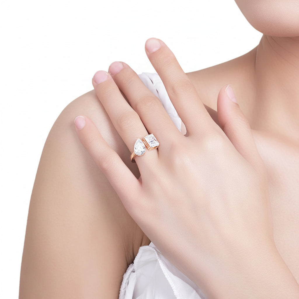 Close-up of a hand wearing pear & emerald moissanite ring on a white background