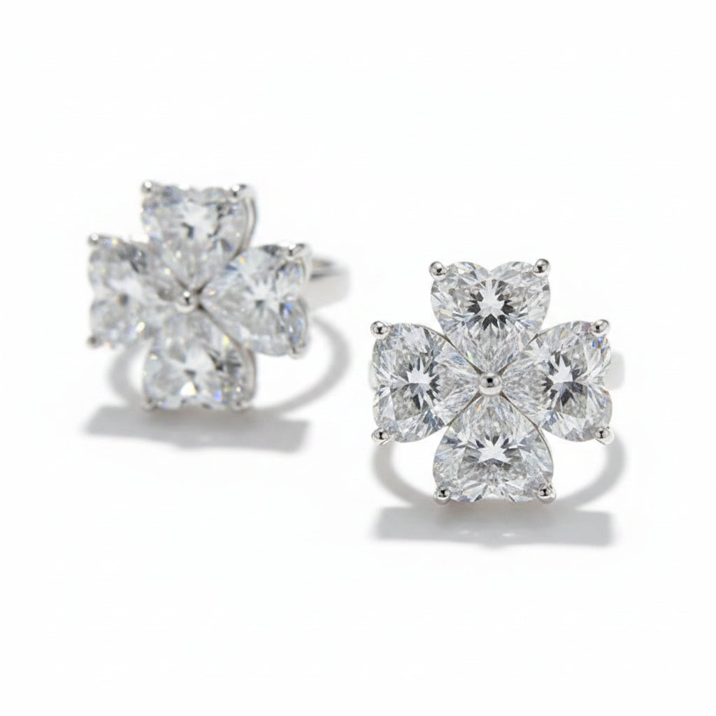 Pair of moissanite diamond stud earrings on a reflective surface with a blurred background