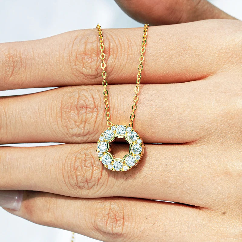Gold necklace with a moissanite diamond pendant held between fingers