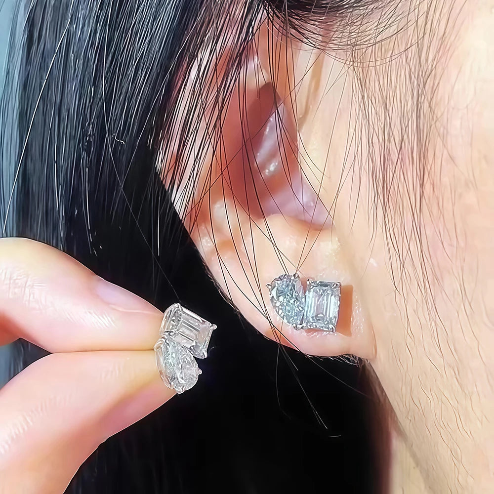 Close-up of diamond earrings being worn and held with a hand.