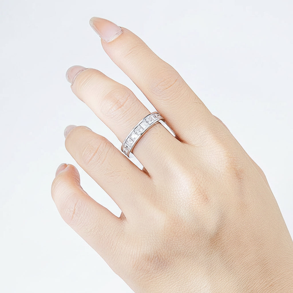 Hand wearing a silver ring with moissanites against a white background