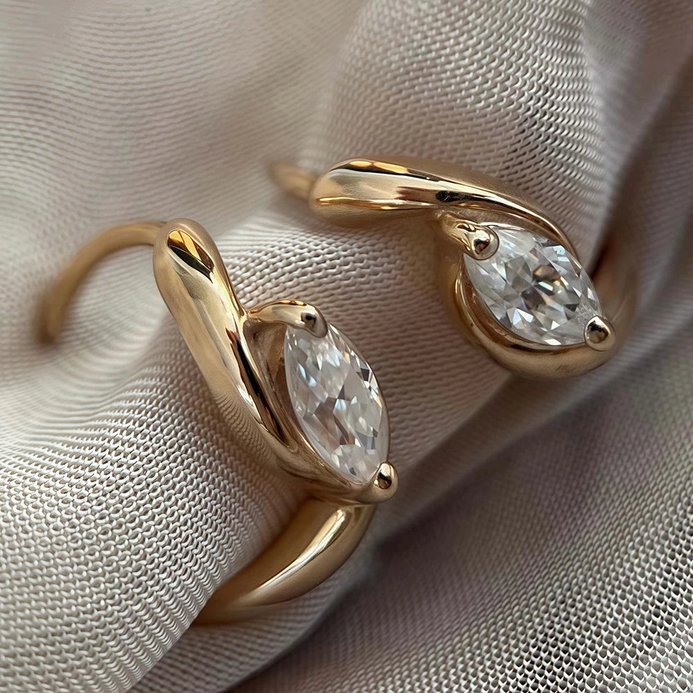 Gold earrings with teardrop-shaped gemstones on a beige fabric background