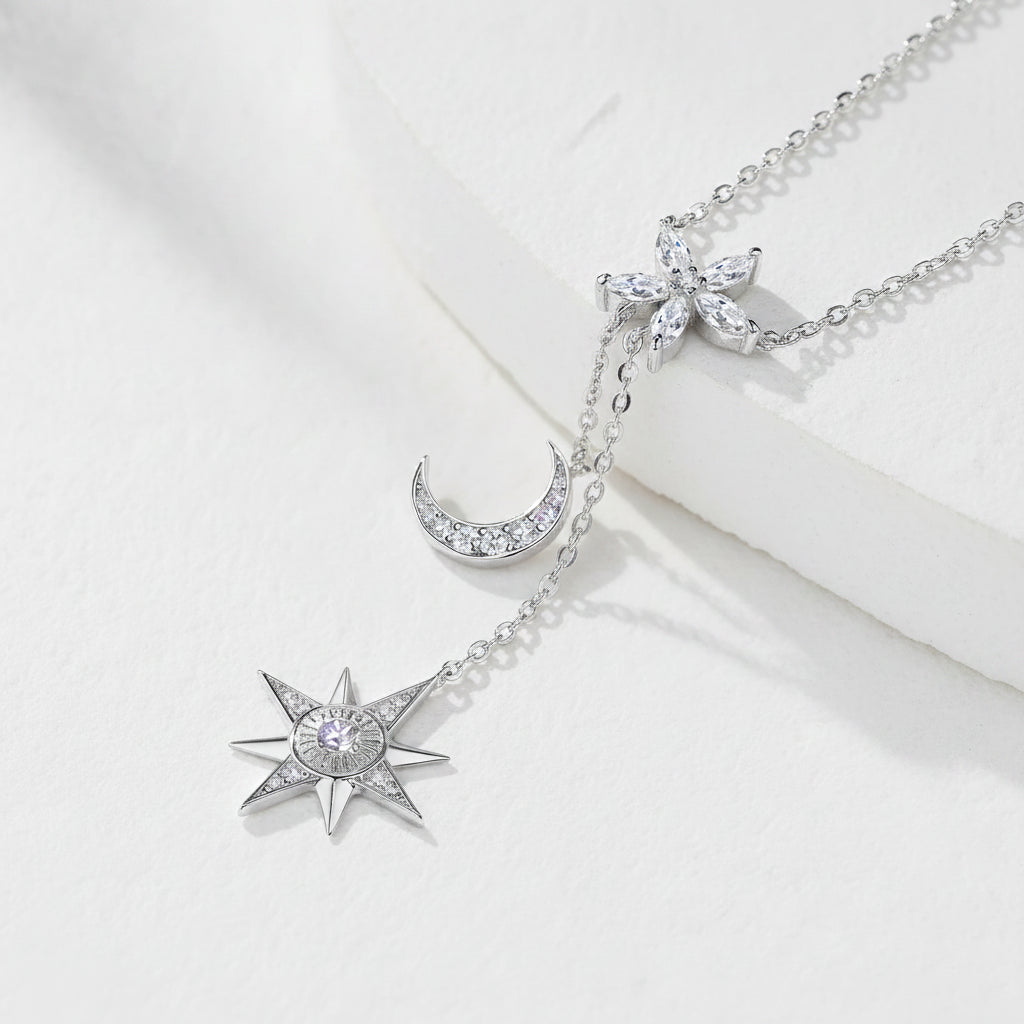 Silver necklace with star and moon pendants on a textured white surface