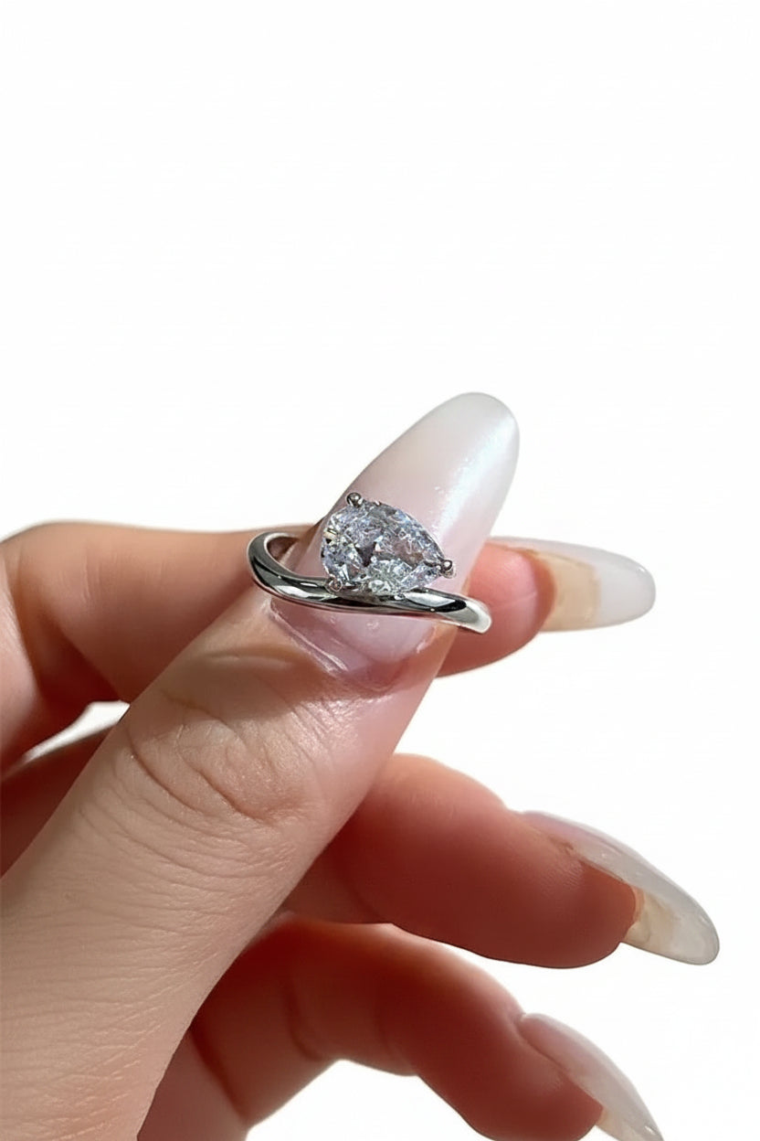 Diamond ring held in a hand with a neutral background