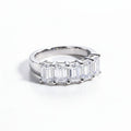 Silver ring with emerald-cut gemstones on a white surface