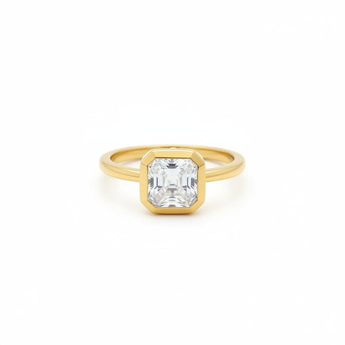 Gold ring with a asscher moissanite diamond on a white surface