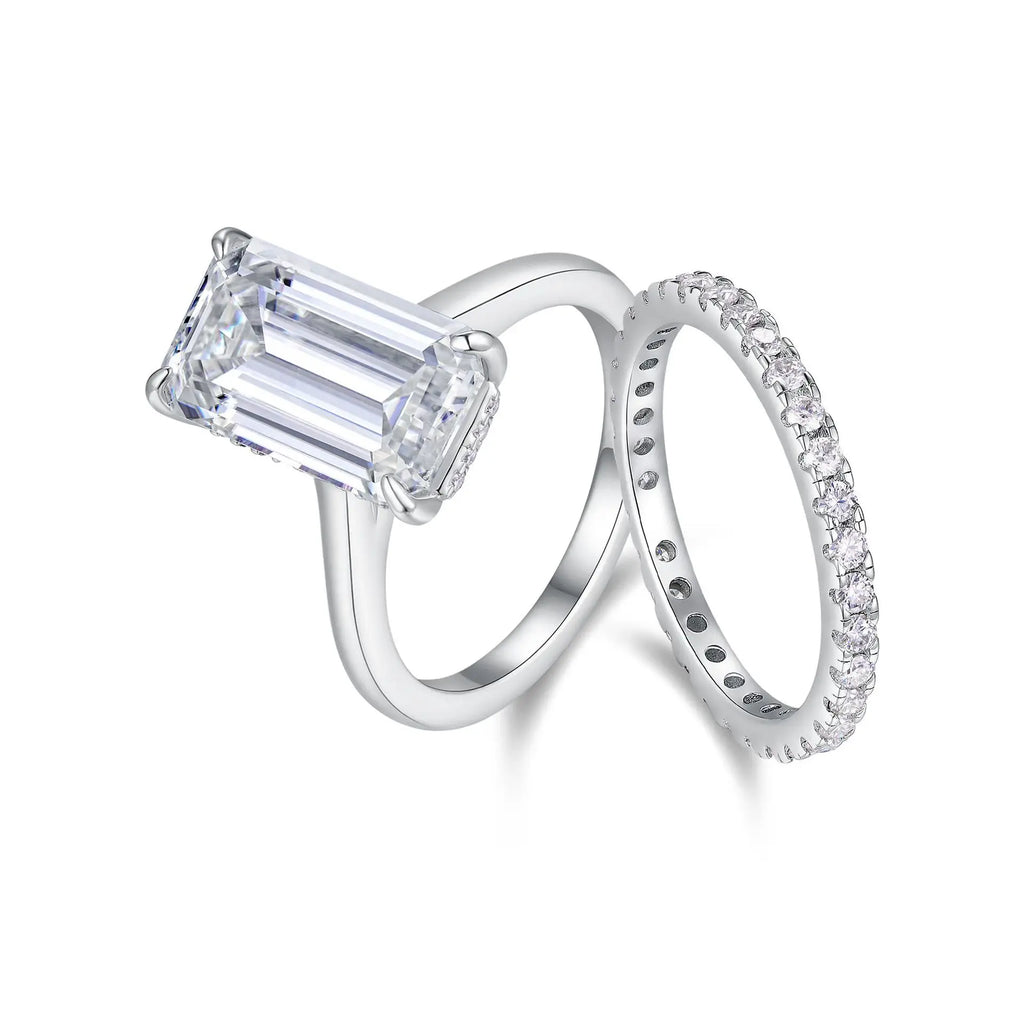 Diamond ring with emerald-cut center stone and matching band on a white background