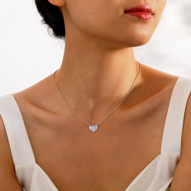 Necklace with a heart-shaped pendant worn by a person against a neutral background