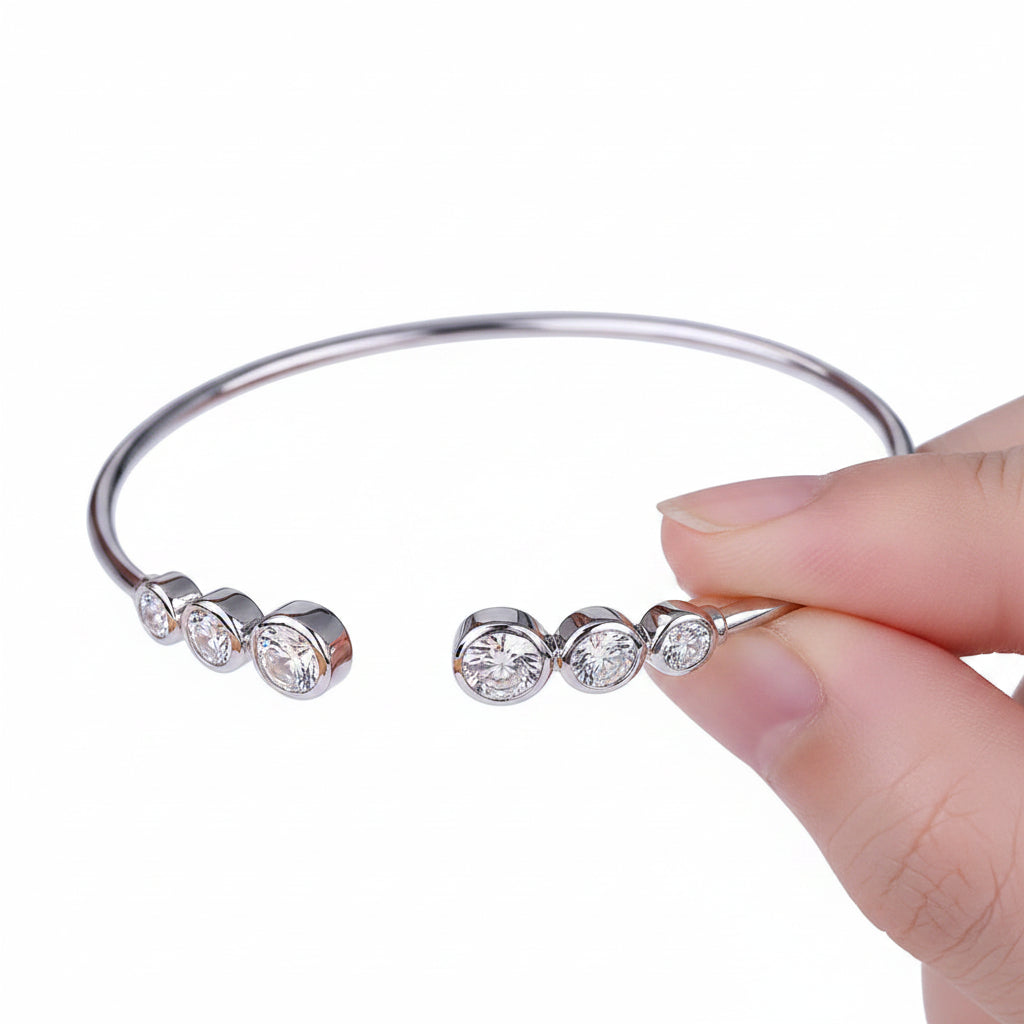 Silver ring held between fingers against a white background