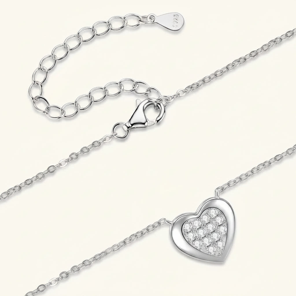 Silver heart-shaped necklace with clear gemstones on a white background