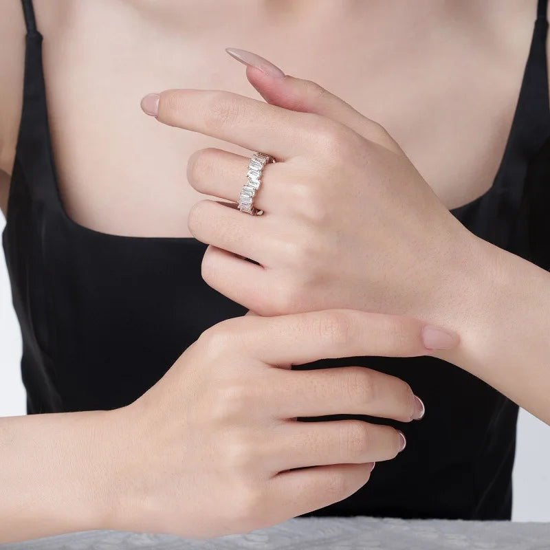 Close-up of a hand wearing a moissanite ring with a blurred background