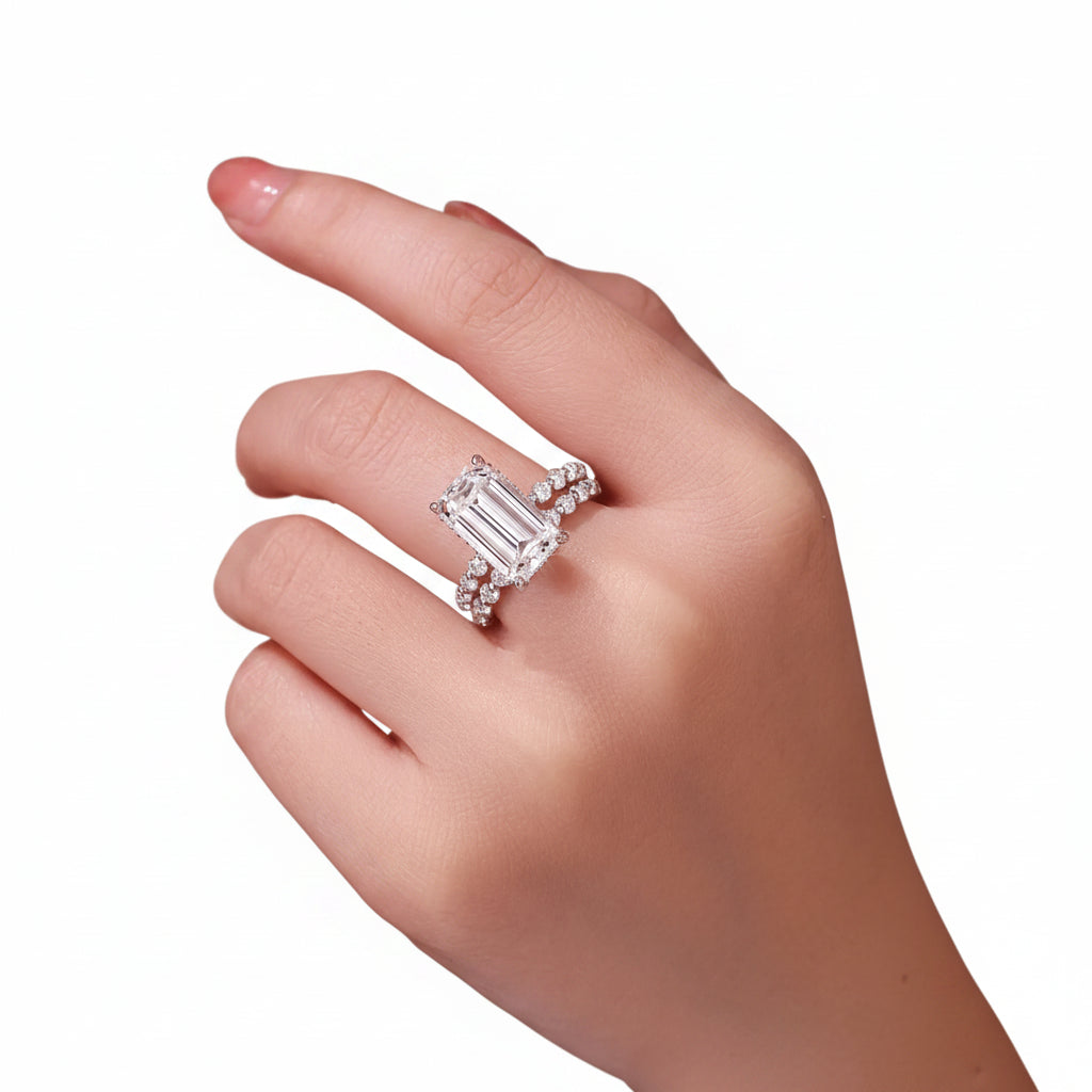 Close-up of a hand wearing a emerald moissanite diamond ring with a white background