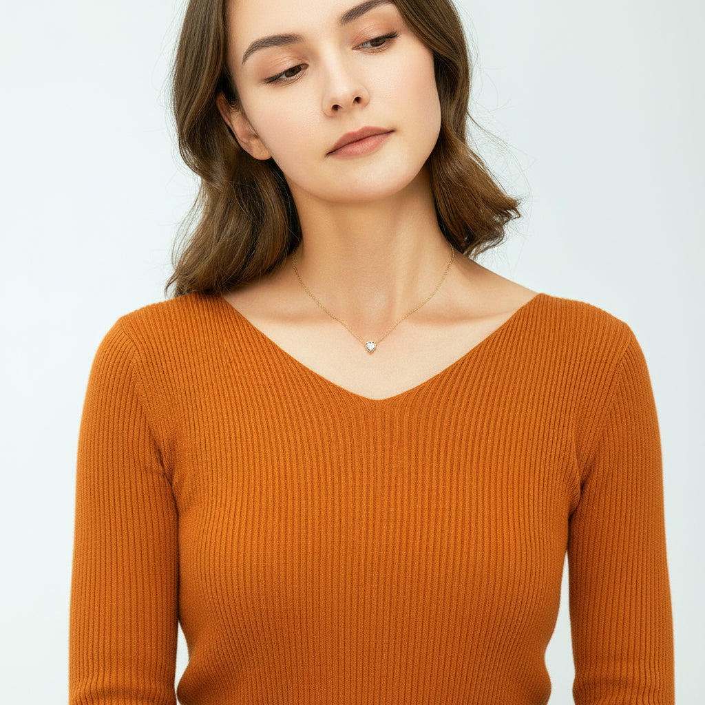 Person wearing a delicate necklace with a heart-shaped pendant on a plain background