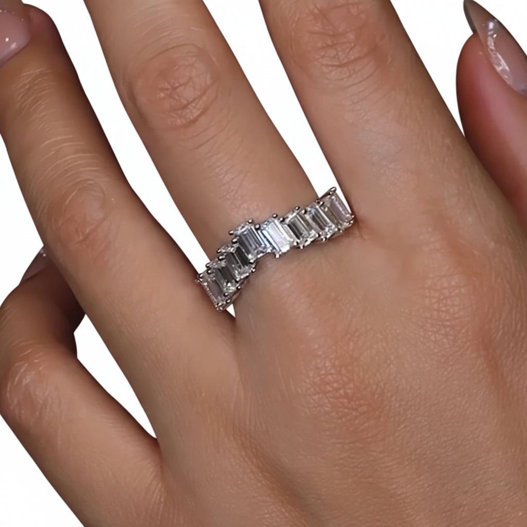 Close-up of a hand wearing a moissanite ring with emerald-cut stones.