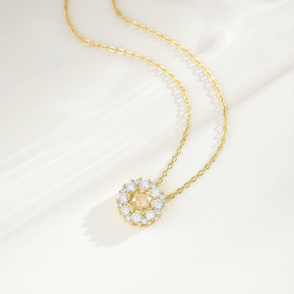 Gold necklace with a round-shaped pendant on a white background