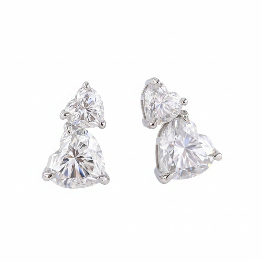 Pair of heart-shaped moissanite diamond earrings on a white background