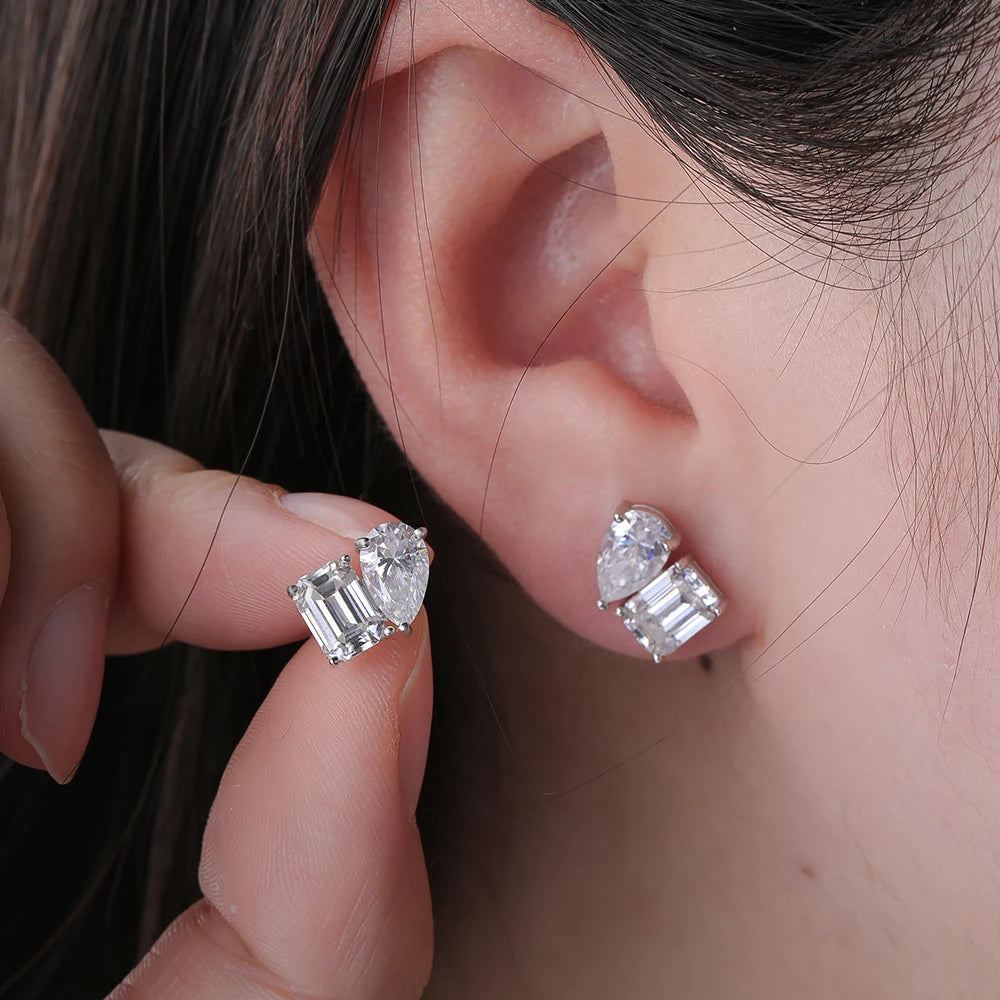 Close-up of a person wearing diamond earrings with one hand holding another earring.