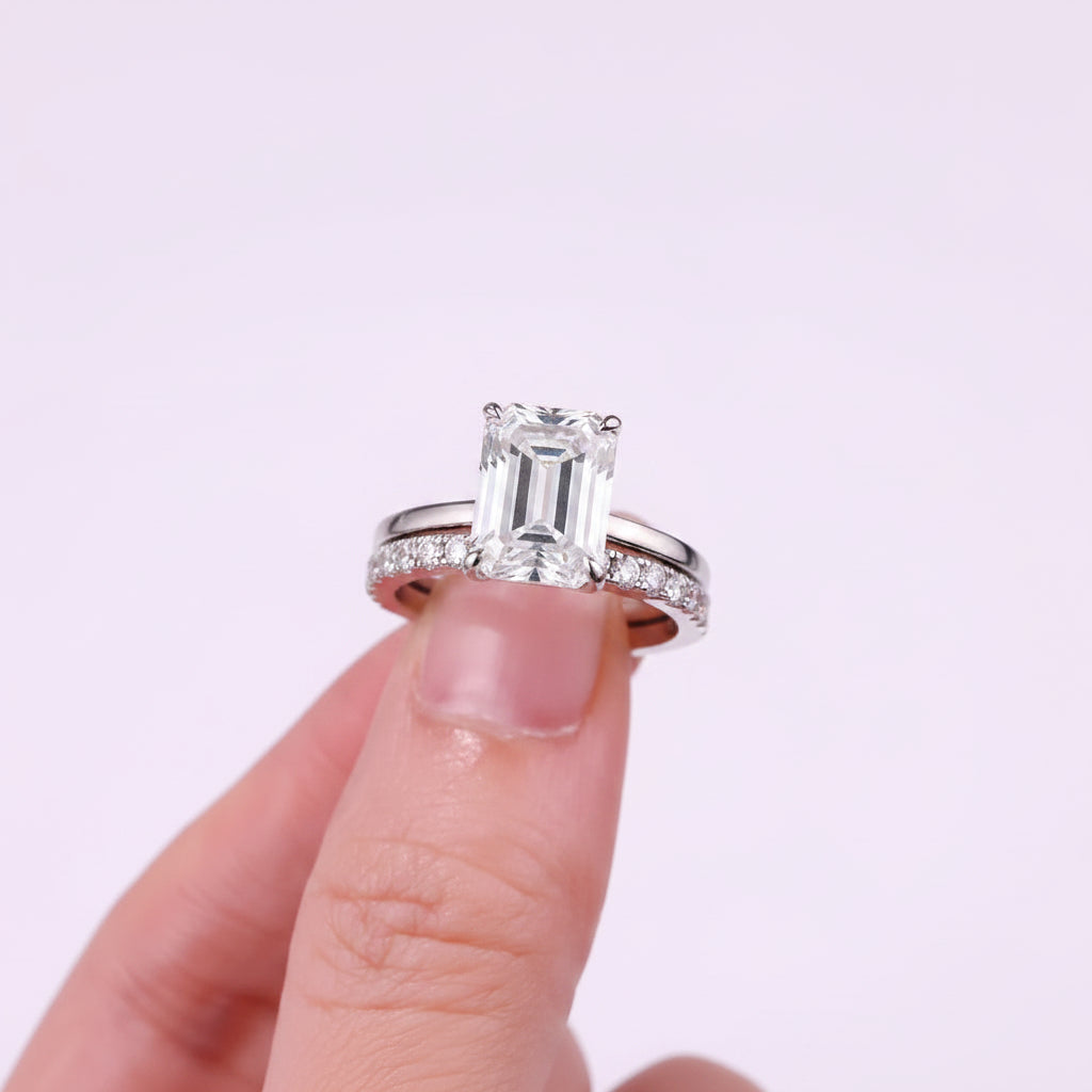 Diamond ring held on a finger against a white background