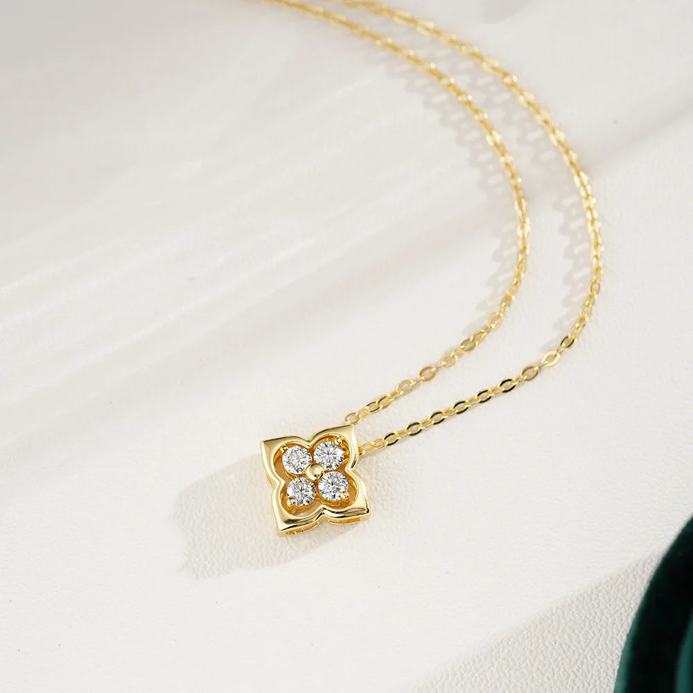 Gold necklace with a clover-shaped pendant on a light background