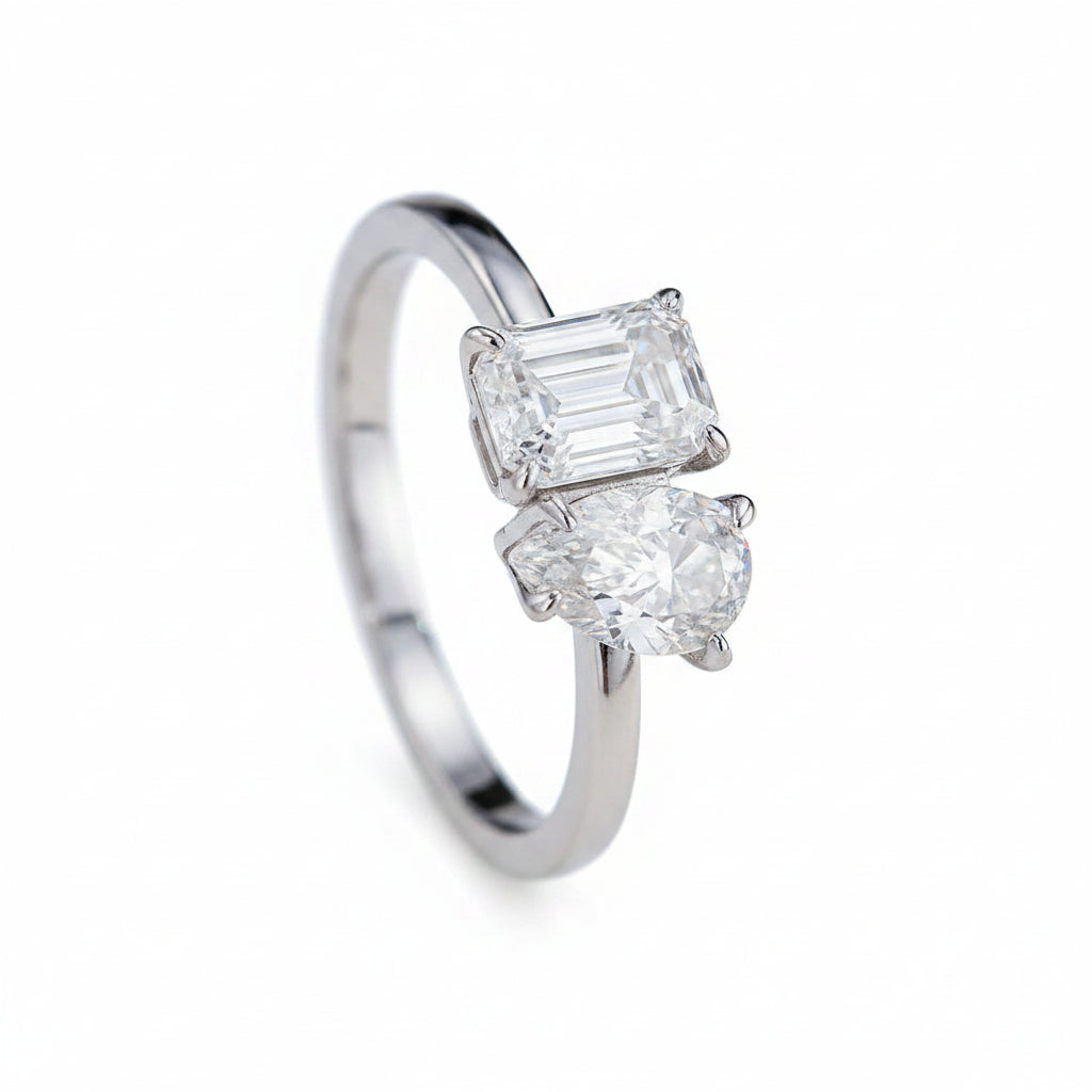 Diamond ring with two prominent gemstones on a white surface