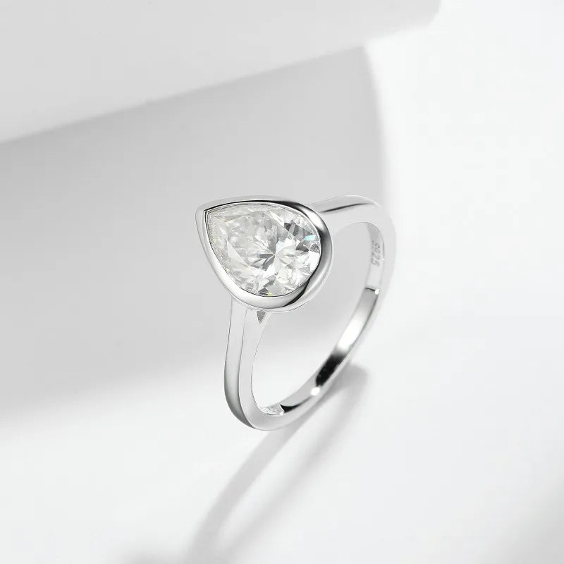 Silver ring with a clear pear moissanite gemstone on a light gray background