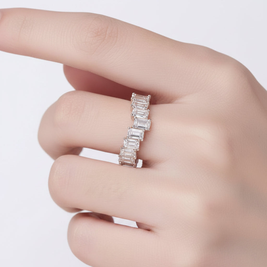Rose gold ring with moissanites on a hand.