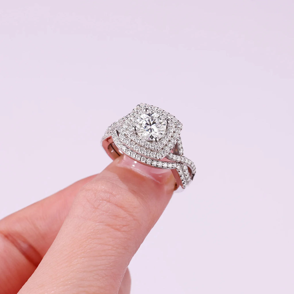 Moissanite diamond ring held on a finger against a light background