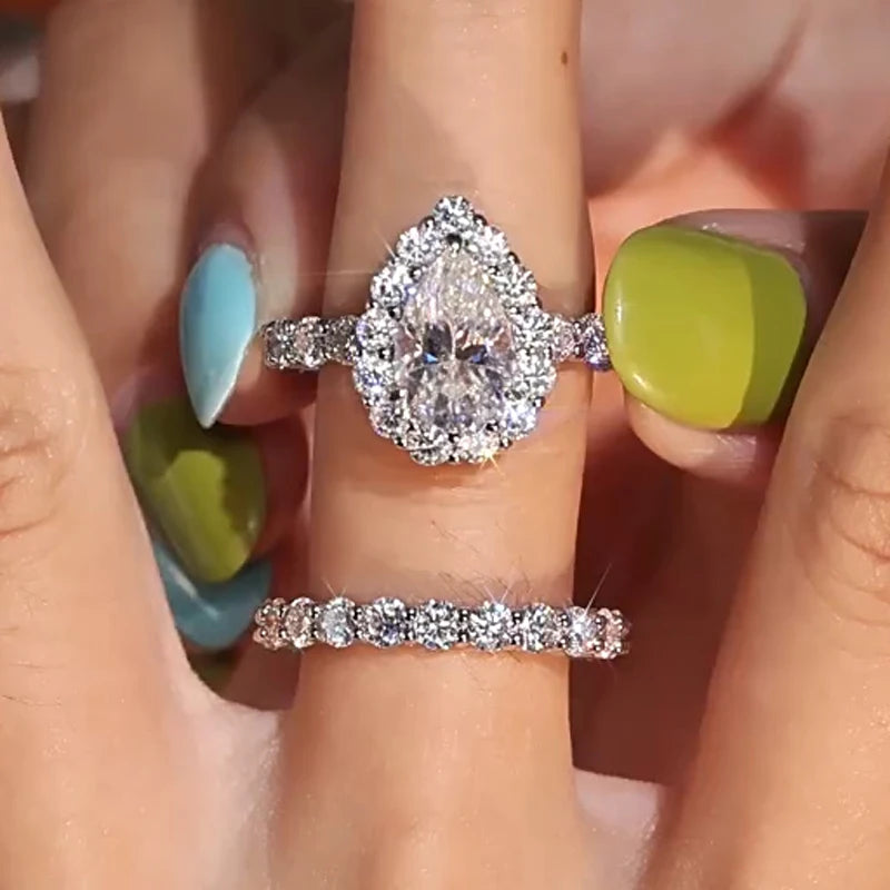 Close-up of a hand wearing two moissanite rings with colorful nail polish.