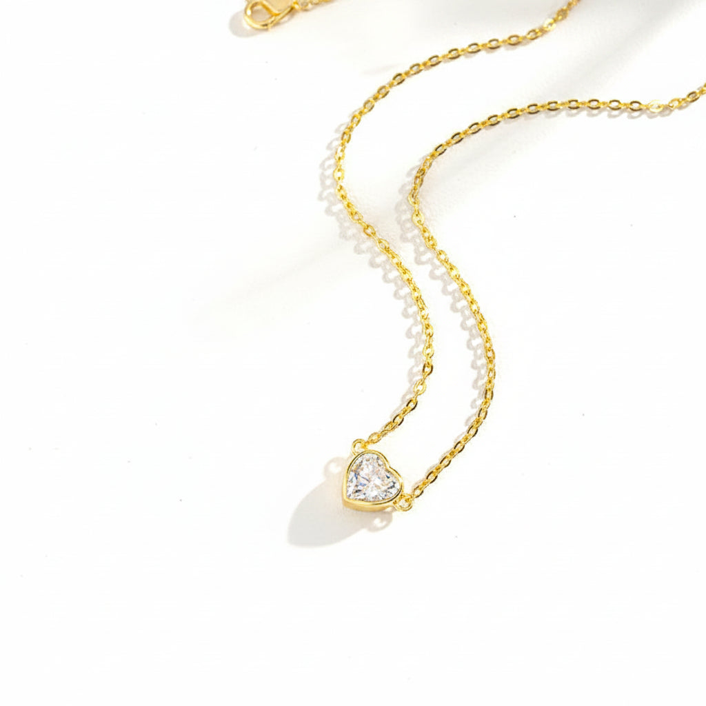 Gold necklace with a heart-shaped pendant on a white background