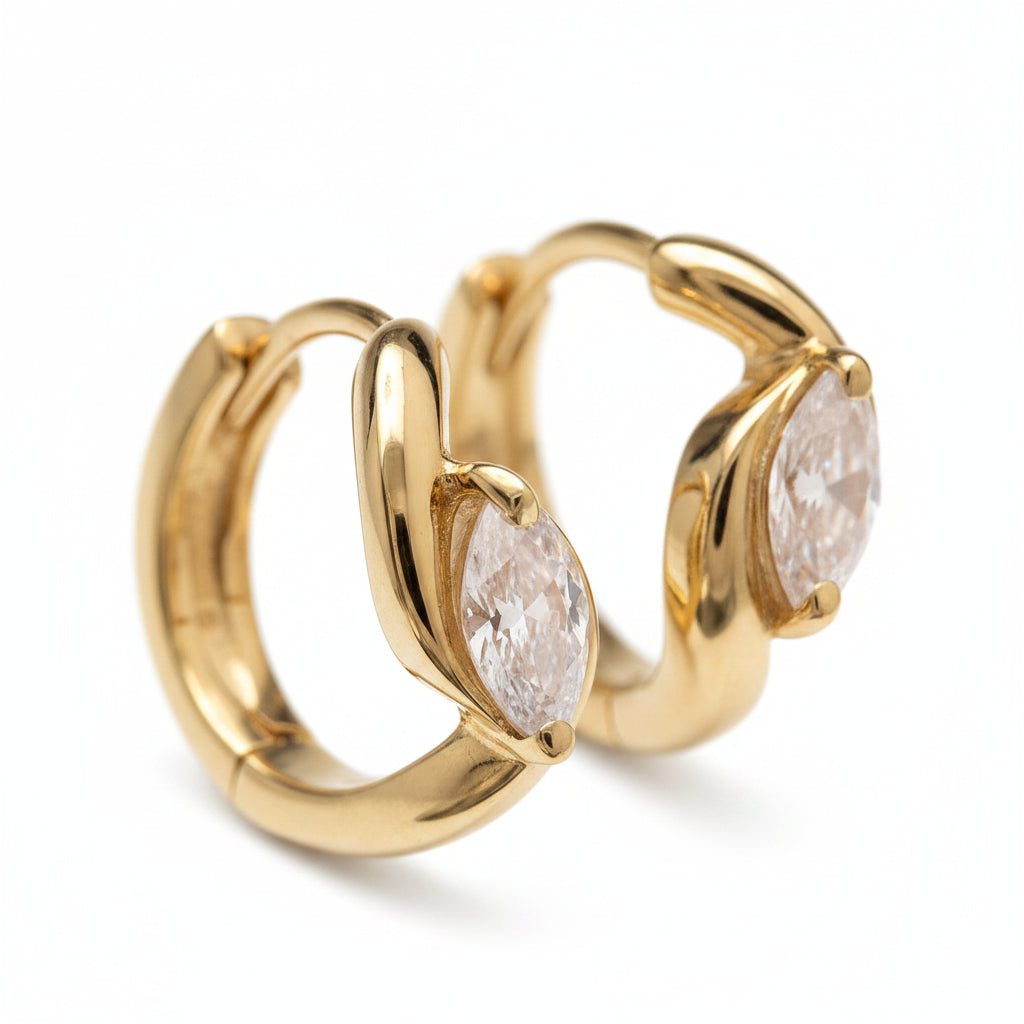 Gold hoop earrings with pear-shaped gemstones on a neutral background