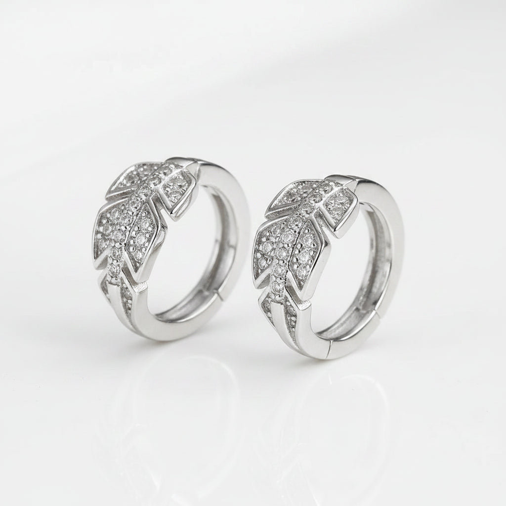 Two silver rings with feather designs on a white surface